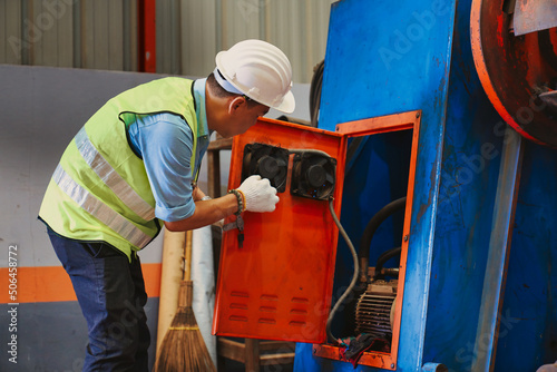 Asian mechanic worker try to maintenance mahcine in metal sheet factory photo