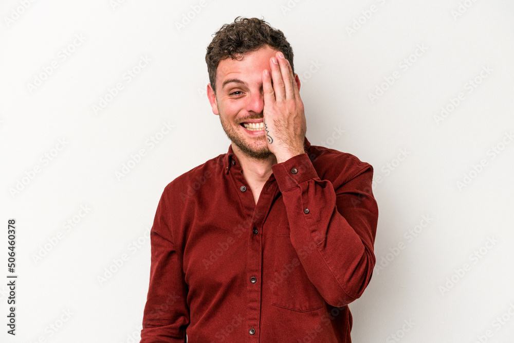 Young caucasian man isolated on white background having fun covering half of face with palm. Young caucasian man isolated on white background having fun covering half of face with palm.