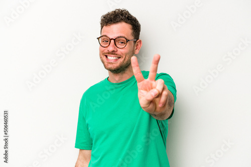 Young caucasian man isolated on white background joyful and carefree showing a peace symbol with fingers.