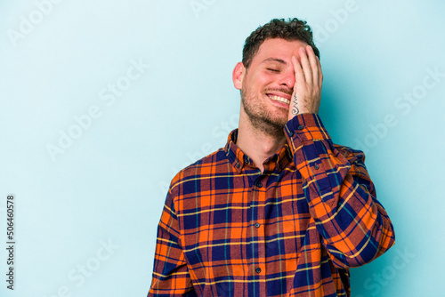 Young caucasian man isolated on blue background laughing happy, carefree, natural emotion.