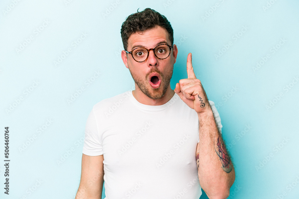 Young caucasian man isolated on blue background pointing upside with opened mouth. Young caucasian man isolated on blue background pointing upside with opened mouth.