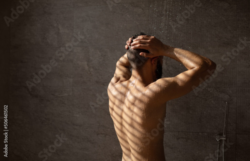 Rear back view of young man washing his body and head