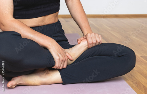Woman stretching her foot while sitting on an exercise mat at the yoga studio.