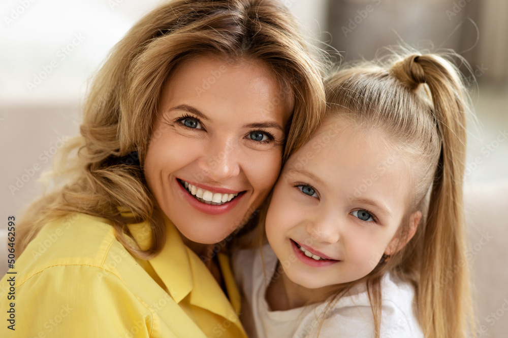 Cheerful Middle Aged Mom And Little Daughter Hugging At Home Cheerful Middle Aged Mom And Little Daughter Hugging At Home