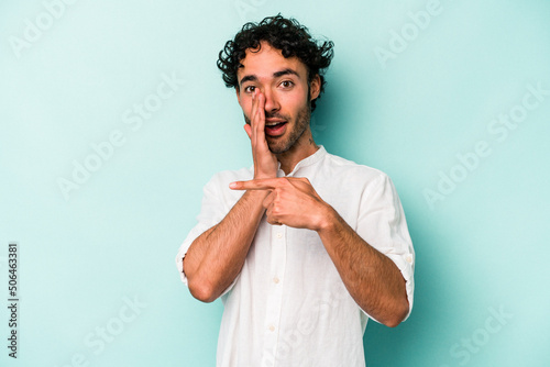 Young caucasian man isolated on white background saying a gossip, pointing to side reporting something.