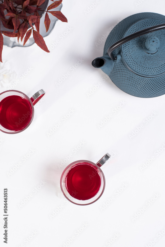 Dos tazas transparentes de té de bayas con tetera de hierro azul sobre una mesa blanca. Vista superior Dos tazas transparentes de té de bayas con tetera de hierro azul sobre una mesa blanca. Vista superior