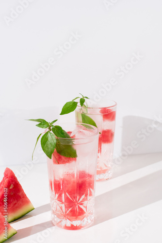 Dos vasos de zumo de sandía con trozos de sandia y hielo sobre fondo claro 