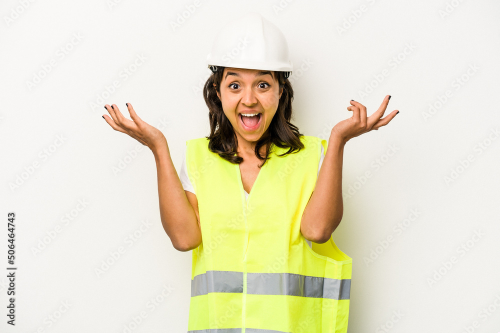 Young laborer hispanic woman isolated on white background receiving a pleasant surprise, excited and raising hands.