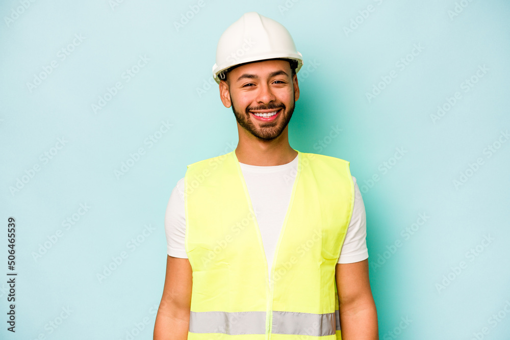 Young laborer hispanic man isolated on blue background happy, smiling and cheerful. Young laborer hispanic man isolated on blue background happy, smiling and cheerful.