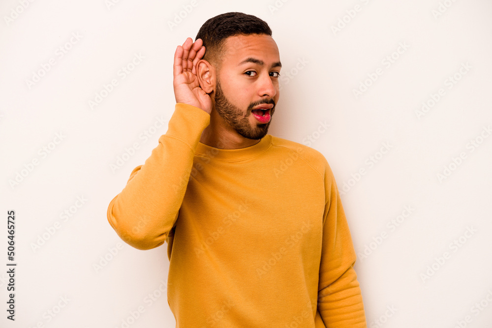 Young hispanic man isolated on white background trying to listening a gossip. Young hispanic man isolated on white background trying to listening a gossip.
