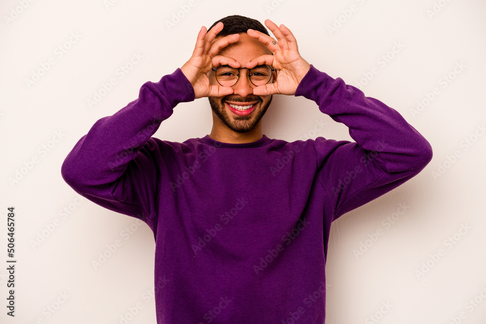 Young hispanic man isolated on white background showing okay sign over eyes Young hispanic man isolated on white background showing okay sign over eyes
