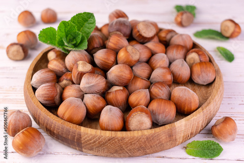 Hazelnuts in a wooden bowl on a white background. 