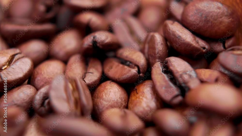 Freshly roasted coffee beans. Fragrant dark seeds falling in slow motion. Macro. Rotation Freshly roasted coffee beans. Fragrant dark seeds falling in slow motion. Macro. Rotation