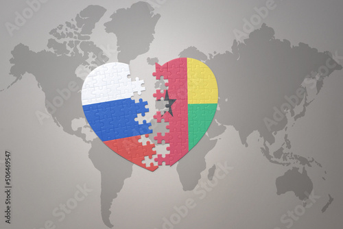 puzzle heart with the national flag of russia and guinea bissau on a world map background. Concept.