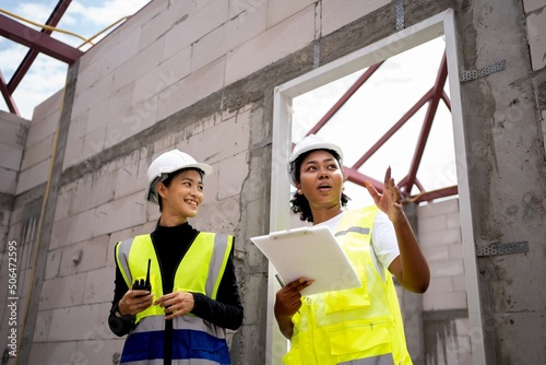 Team of beautiful female engineers inspecting the quality of house construction. Multi-ethnic group of Africans and non-Americans.female holding clipboard.ppe wearing safety firse concept. photo