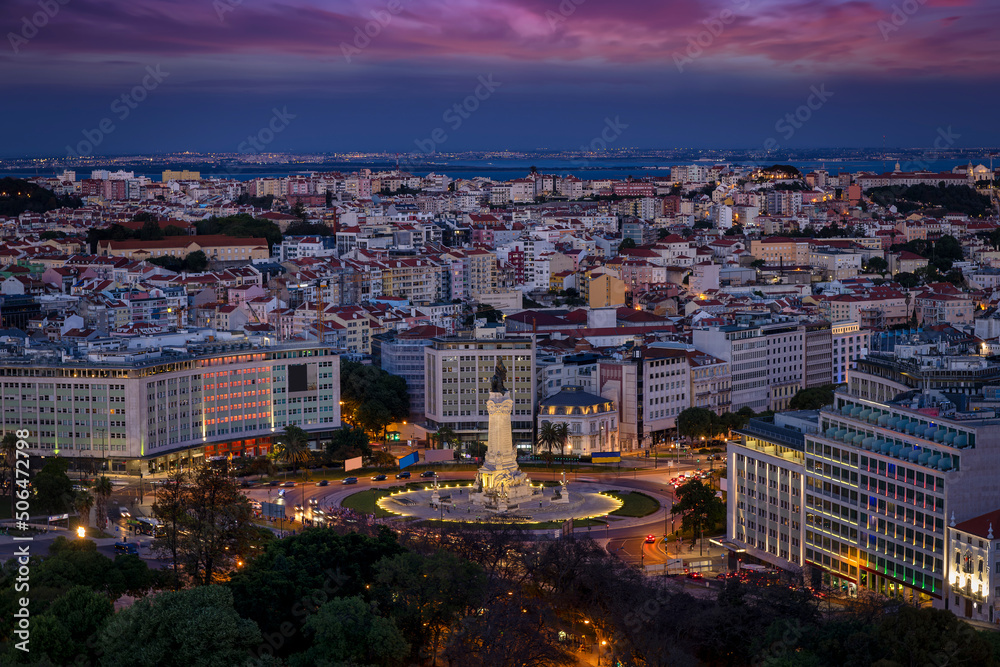 The skyline of Lisbon, Portugal, with Marques de Pombal square and Alfama district in the background during evening time