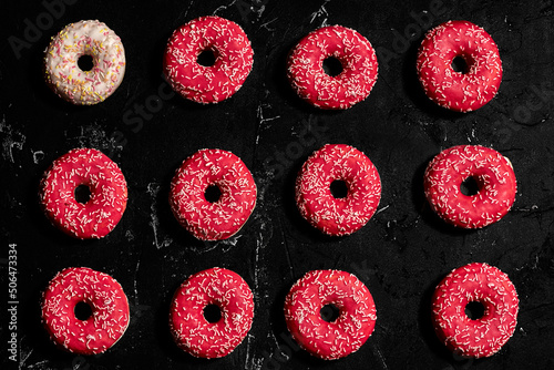 Pattern of Different donuts on black concrete background. Top view.
