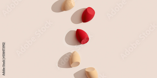 Fotografie Wide banner with makeup sponges for foundation cream on beige background with dark shadows