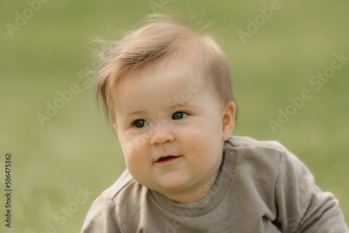 A close portrait of a kind 7-month child who is playing in the meadow.