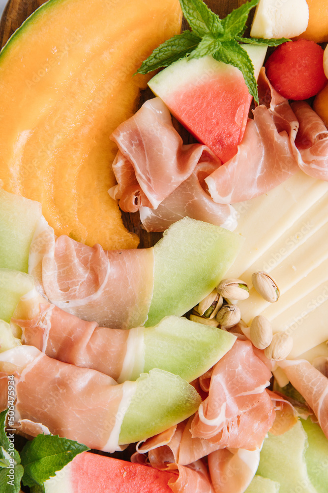 A charcuterie board full of various melons like watermelon, honeydew, and cantaloupe. There is also cheese and pistachios. A charcuterie board full of various melons like watermelon, honeydew, and cantaloupe. There is also cheese and pistachios.