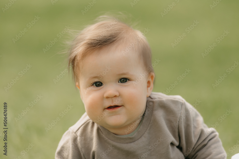 A close portrait of a smiling 7-month child who is playing in the meadow.