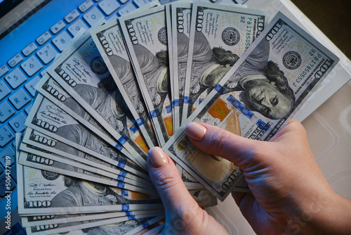 female hands holding fan of money hundred dollars banknotes