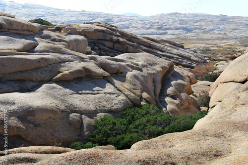 Rounded volcanic layered stones in the Bektau-Ata tract form a beautiful ravine, at the bottom of the ravine there is a green low bush, a distant view of the stone plateau, summer, sunny