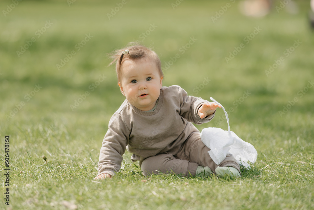 A smiling 7-month child is playing with a white panama hat in the meadow. A smiling 7-month child is playing with a white panama hat in the meadow.