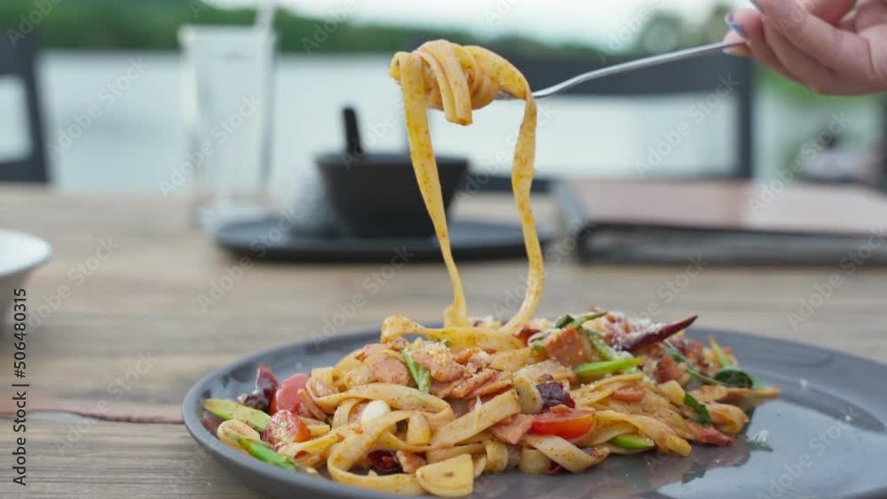 Fork rolling Pasta spaghetti chili bacon on ceramic plate in restaurant