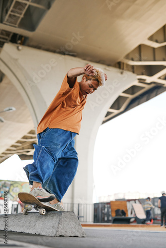 Full length shot of teenager in motion doing skateboarding tricks in urban skatepark