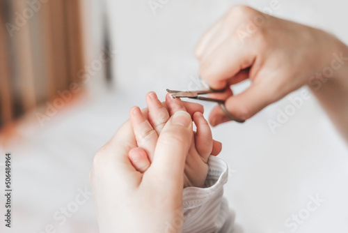 mom cuts baby s fingernails with special children s scissors at home. close up. copy space. manicure for newborns. white background