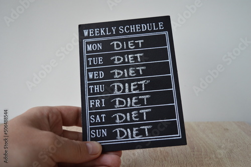 A board with a weekly schedule on which the diet is written in chalk from Monday to Sunday. Adherence to a diet plan seven days a week