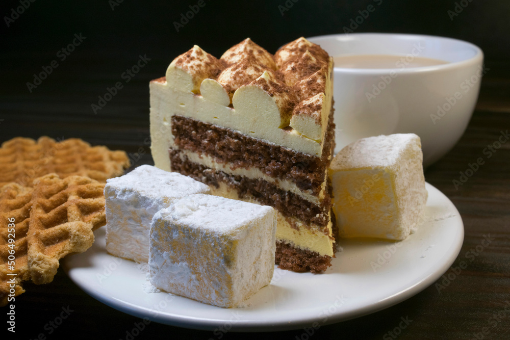 Piece of cake with turkish delight on white plate and waffles. Piece of cake with turkish delight on white plate and waffles.
