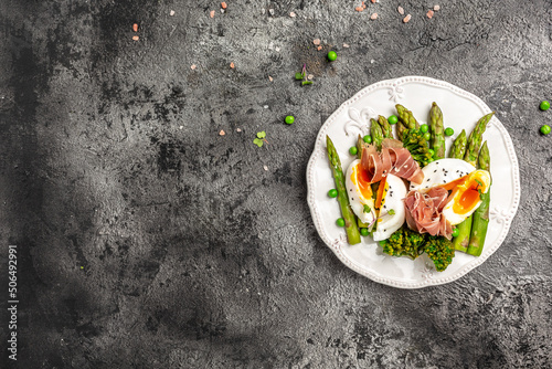 Ketogenic diet meal Poached egg with asparagus spears and prosciutto on a dark background. banner, menu recipe place for text, top view