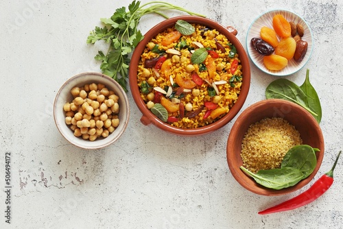 Vegan Moroccan Bulgur with Chick Peas, spinach, dried apricots and date fruit. Traditional African Tajine dish. Flat layot