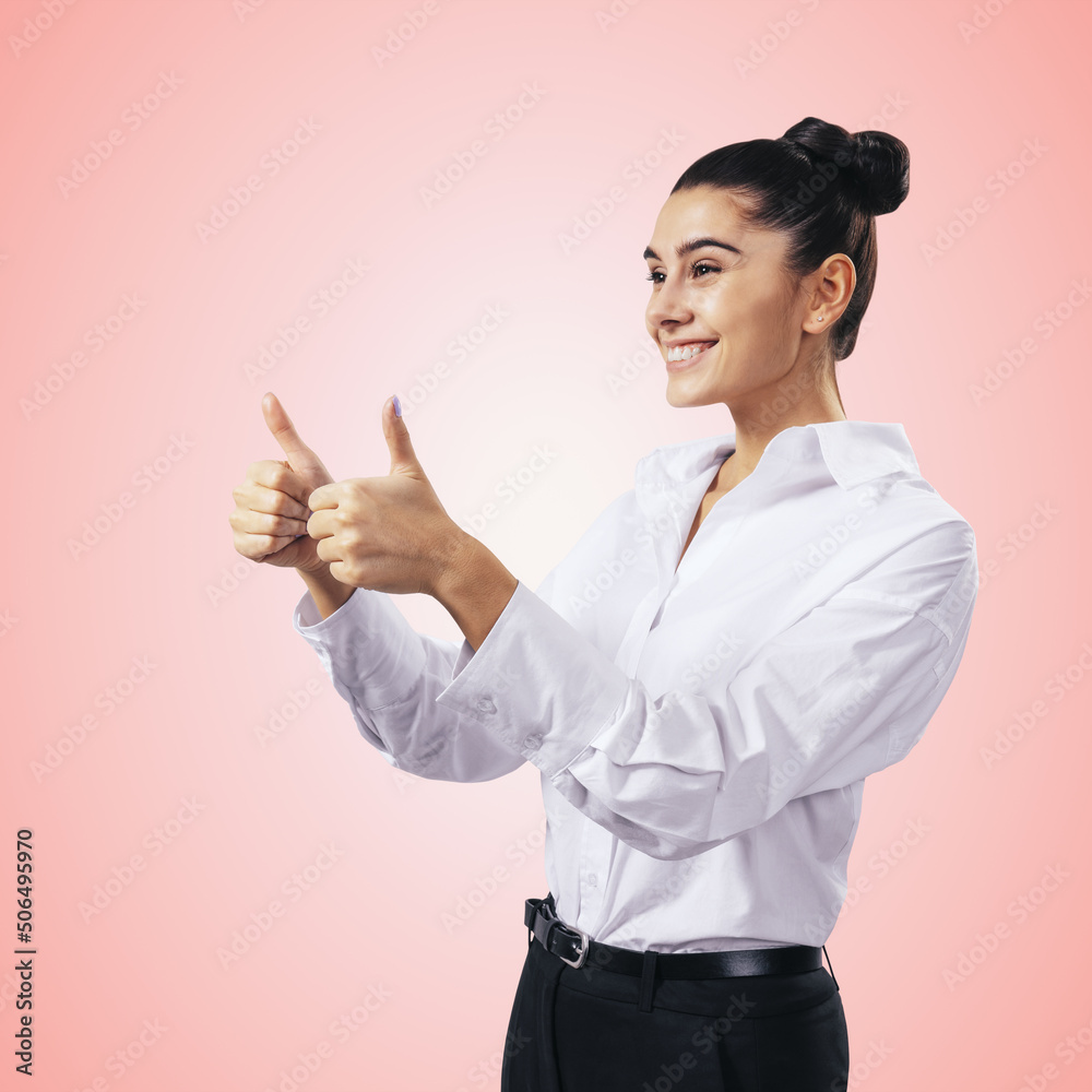 Like concept with happy girl in white shirt holding thumbs up on light pink background, close up, isolated Like concept with happy girl in white shirt holding thumbs up on light pink background, close up, isolated