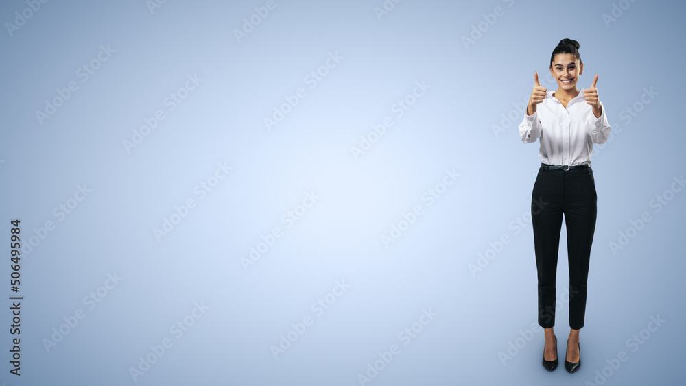 Like concept with happy young businesswoman in white shirt and black trousers holding thumbs up and standing full length on light blue background with empty place for you text, mock up Like concept with happy young businesswoman in white shirt and black trousers holding thumbs up and standing full length on light blue background with empty place for you text, mock up