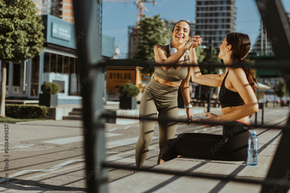 Fototapeta premium Young women in sportswear exercising on a river promenade