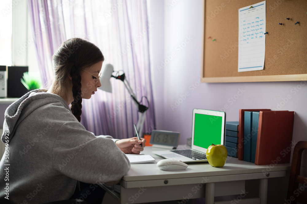 Green screen. A student sits at a desk doing schoolwork. Green screen. A student sits at a desk doing schoolwork.