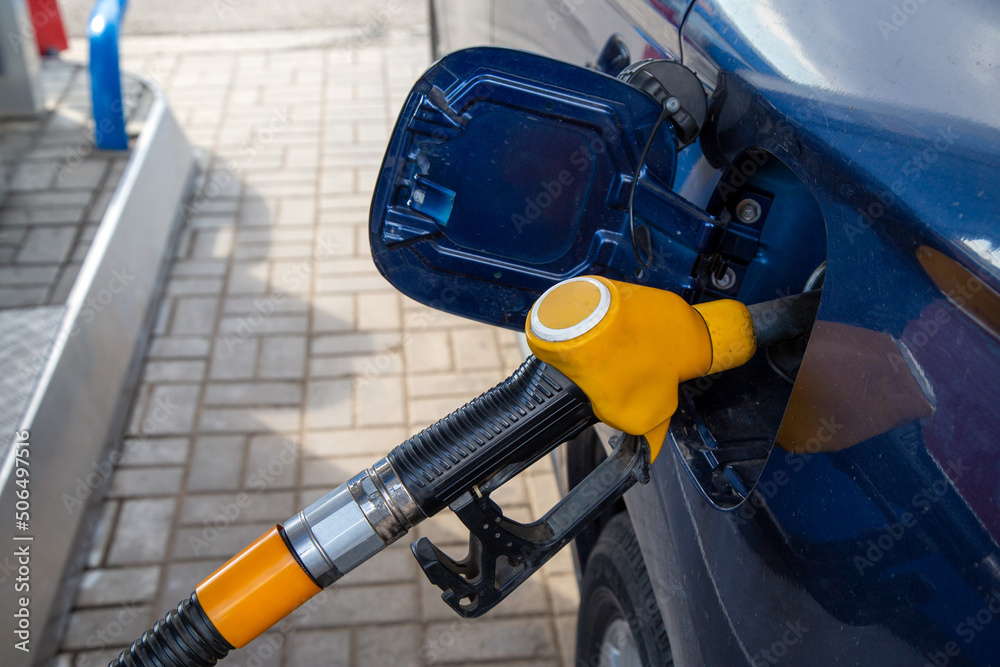 A gasoline filling gun is inserted into the gas tank of a car at a gas station. Fuel for cars, transport.
