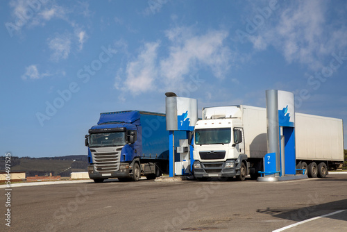 Two trucks pour fuel at a gas station. Highway service.