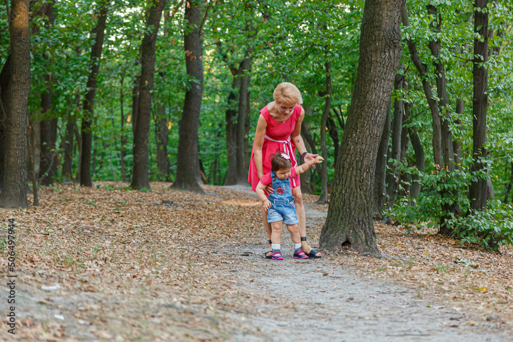 beautiful mother with her daughter walks in the park in summer beautiful mother with her daughter walks in the park in summer
