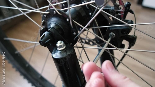 A bicycle mechanic man repairs a bicycle in a workshop. Cyclist's hand with a wrench adjusts the brake pads. photo