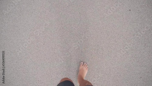 POV first person view looking at the ground walking backwards in the sand with bare feet in the daytime