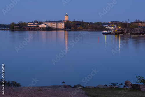 Suomenlinna fortress across the river. A lighthouse casting reflections on the calm sea. photo