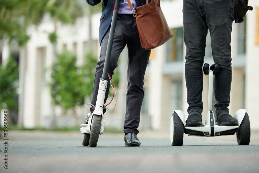 © DragonImages - Cropped image of university lecturers riding on electric scooters to campus