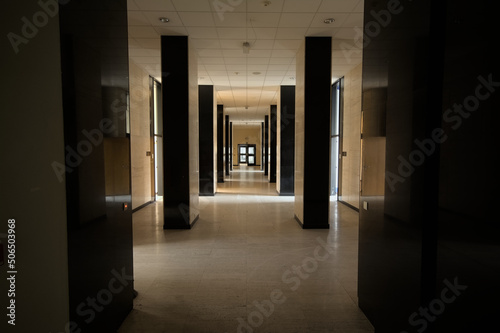 Fancy hallway of an office building, with walls in marble and pilars in shine black granite photo