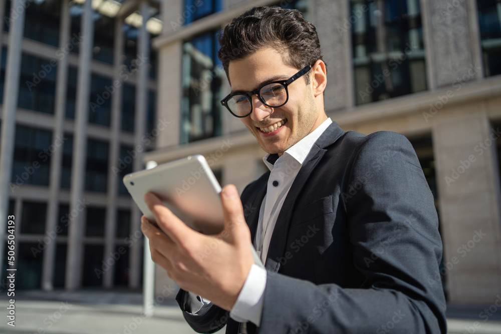 Uses a tablet writes a message to a client a man in glasses and a formal suit a businessman Uses a tablet writes a message to a client a man in glasses and a formal suit a businessman