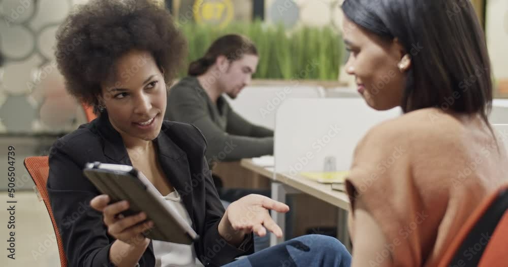 Businesswomen discussing data on tablet Businesswomen discussing data on tablet