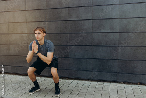 male athlete doing exercises on a black wall